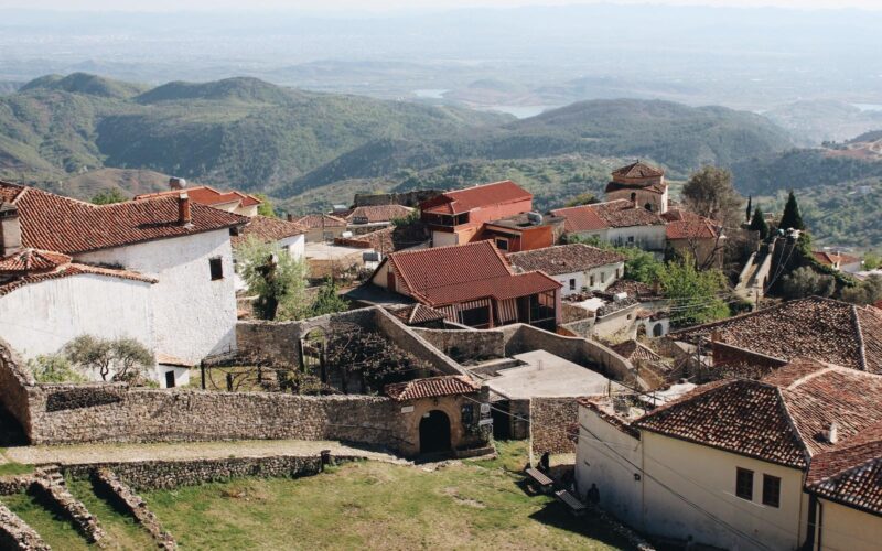 white and brown concrete houses near green grass field during daytime